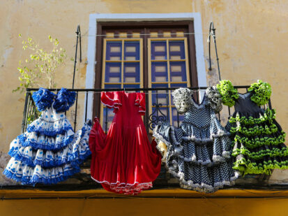 Die für Spanien typischen traditionellen Trachten, hängen in vier varianten über einen spanischen Balkon. Die sogenannten Flamencokleider sind mit prachtvollen Farben und Rüschen bestickt.