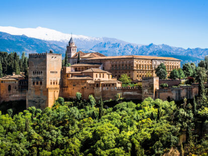 Die Stadtburg Alhambra die sich auf dem Sabikah-Hügel in Granada Spanien befindet. Sie ist umgeben von einer saftig grünen Landschaft und Bergen.