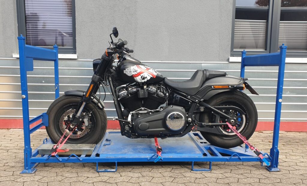 Zu sehen ist eine Harley-Davidson, die auf einem von uns speziell angefertigtem Motorradgestell verzurrt ist. In diesen Gestellen werden alle Motorräder auf unserem LKW verladen.